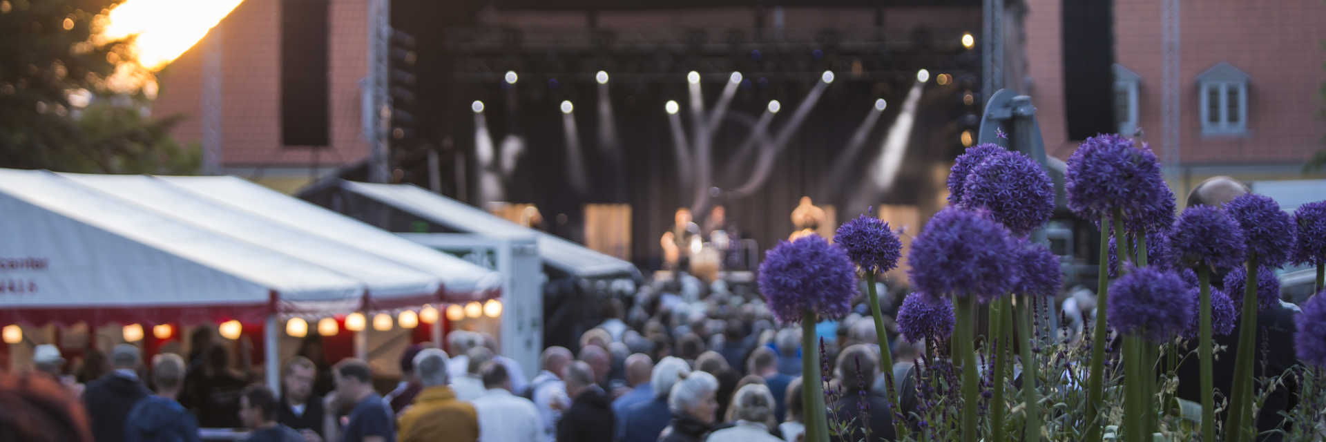 Personer foran scene med blomster i forgrunden